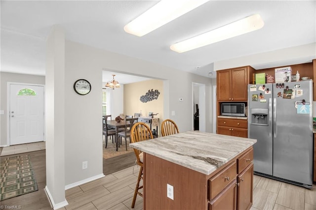 kitchen featuring brown cabinetry, wood tiled floor, a kitchen breakfast bar, a center island, and stainless steel fridge with ice dispenser