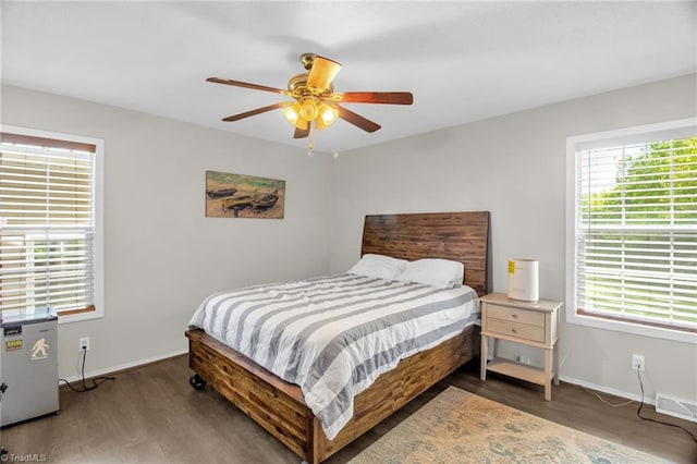 bedroom featuring baseboards, visible vents, multiple windows, and wood finished floors