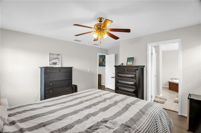bedroom featuring connected bathroom, a ceiling fan, wood finished floors, and visible vents
