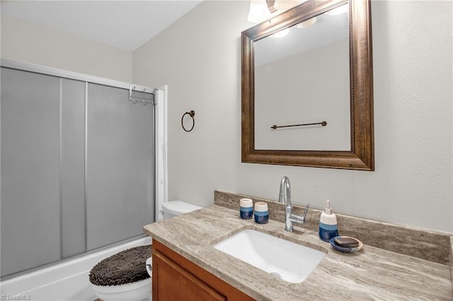 bathroom featuring vanity, combined bath / shower with glass door, and toilet