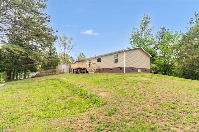 rear view of property featuring a storage unit, a yard, crawl space, and a deck