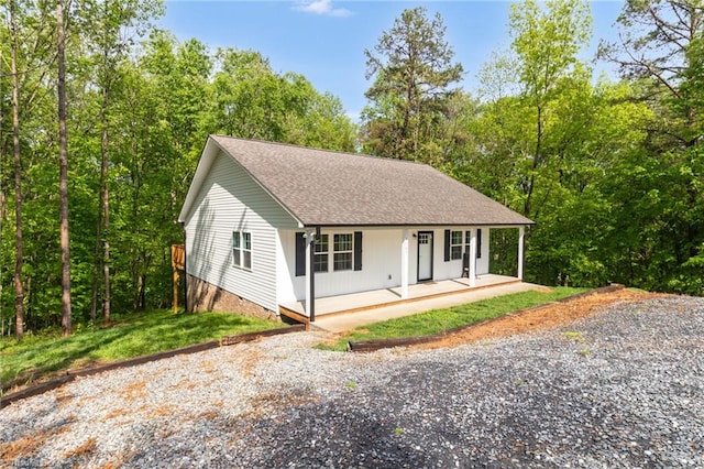 view of front facade featuring a shingled roof, covered porch, and driveway