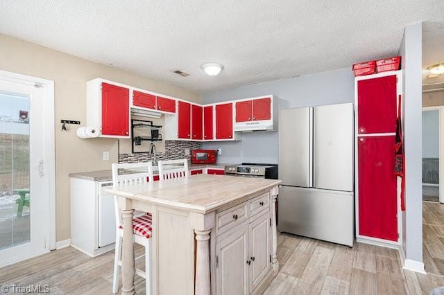 kitchen featuring light wood-type flooring, a textured ceiling, refrigerator, and a kitchen island