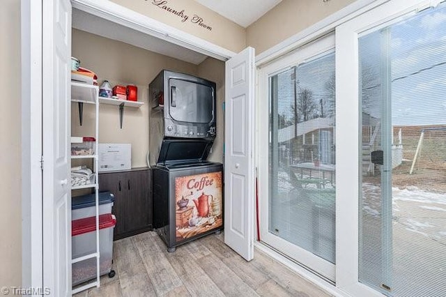 clothes washing area featuring stacked washer and dryer and light hardwood / wood-style flooring