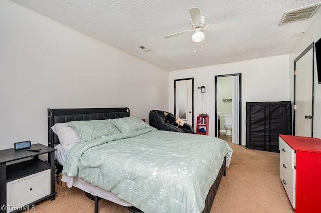 bedroom featuring lofted ceiling, light carpet, ensuite bathroom, ceiling fan, and a textured ceiling