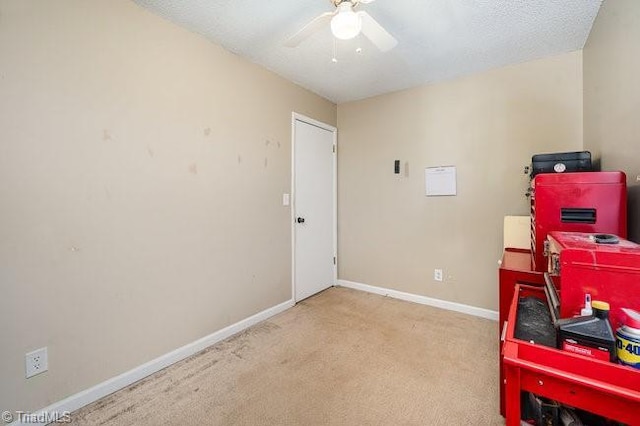 interior space featuring a textured ceiling, ceiling fan, and light carpet