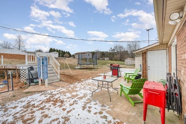 view of patio featuring area for grilling, a shed, and a trampoline