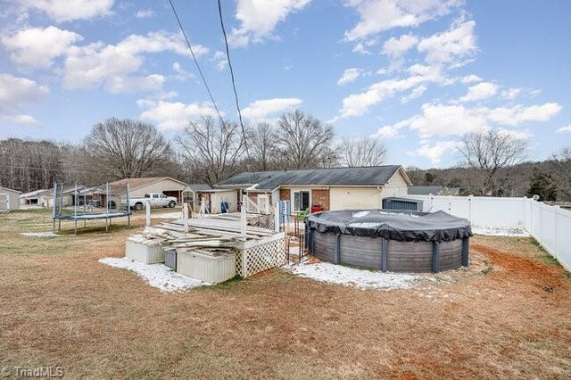 back of property featuring a trampoline and a covered pool