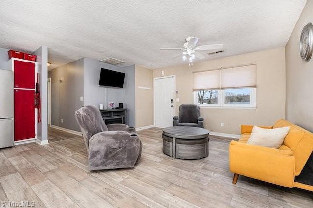 living room featuring ceiling fan, wood-type flooring, and a textured ceiling