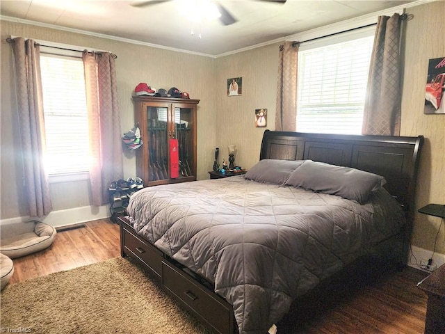 bedroom featuring wood finished floors, multiple windows, ornamental molding, baseboards, and ceiling fan