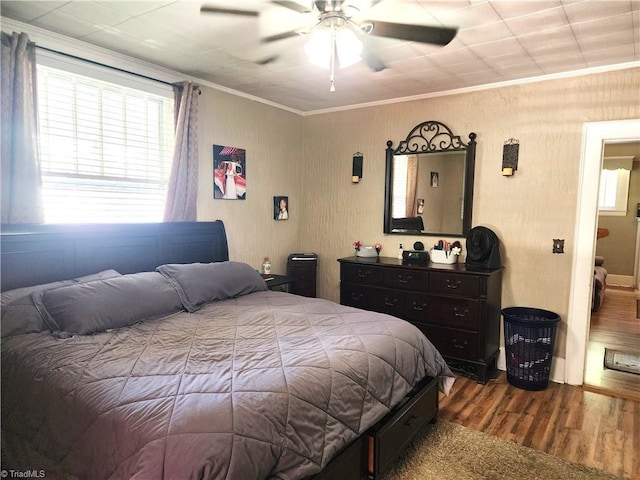 bedroom with wood finished floors, multiple windows, crown molding, and ceiling fan