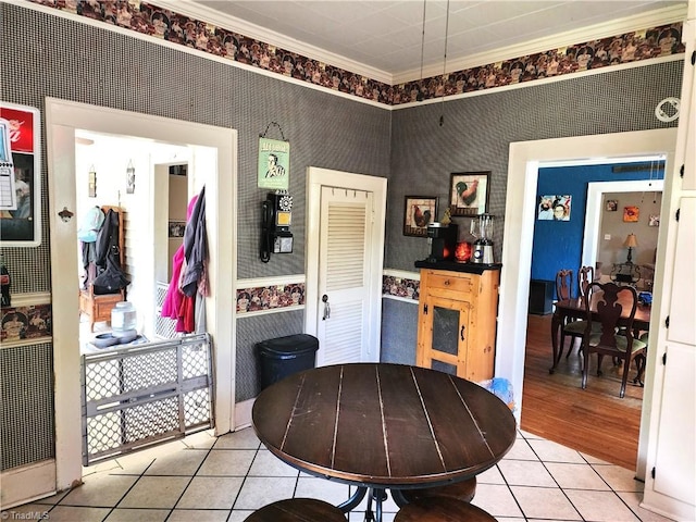 dining space with crown molding, light tile patterned floors, and wallpapered walls