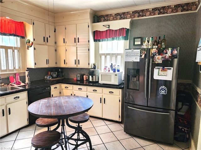 kitchen featuring refrigerator with ice dispenser, white microwave, dark countertops, light tile patterned floors, and crown molding