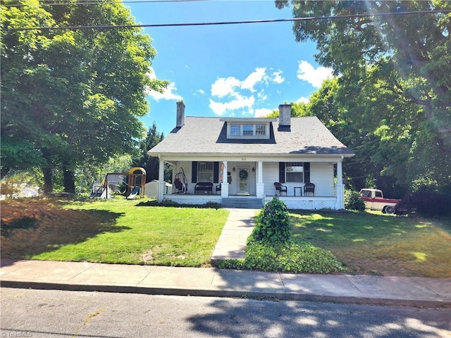 bungalow featuring a chimney, covered porch, and a front yard