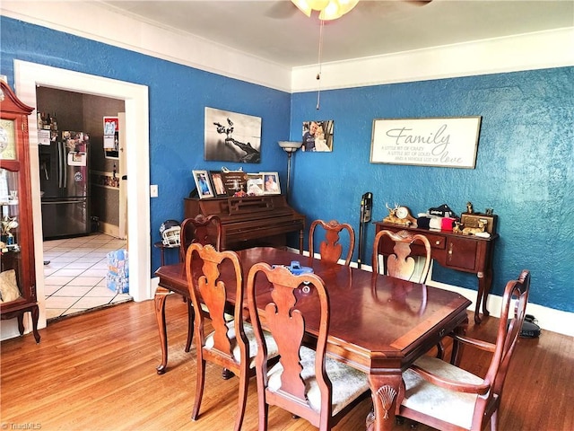dining space with a ceiling fan, wood finished floors, and a textured wall
