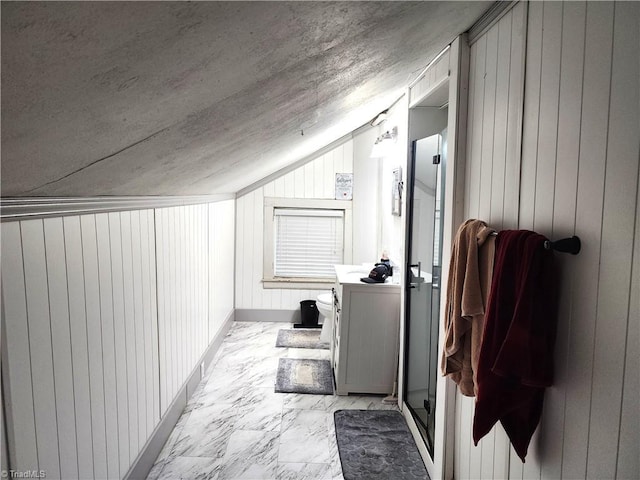 corridor with lofted ceiling, wooden walls, and light marble finish flooring