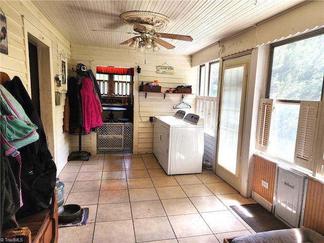 laundry area with washing machine and dryer, light tile patterned floors, wood ceiling, a ceiling fan, and wood walls