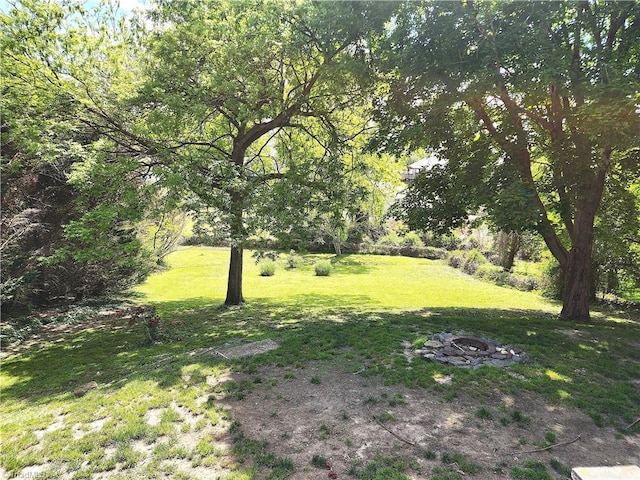 view of green lawn with a fire pit