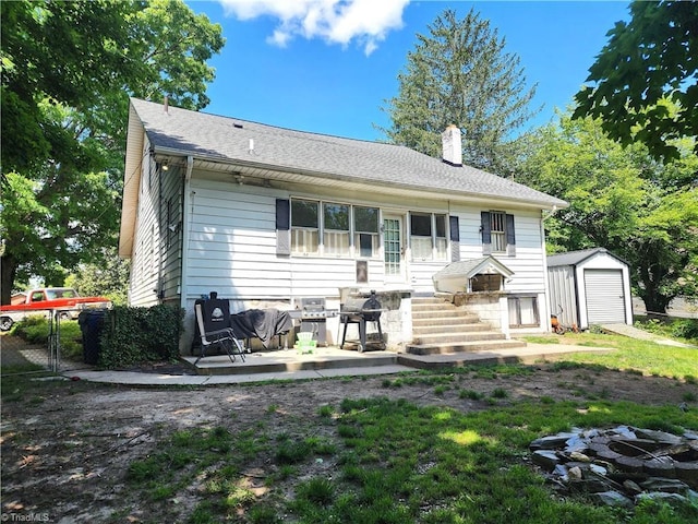 back of house with a chimney, an outbuilding, a detached garage, a storage unit, and fence
