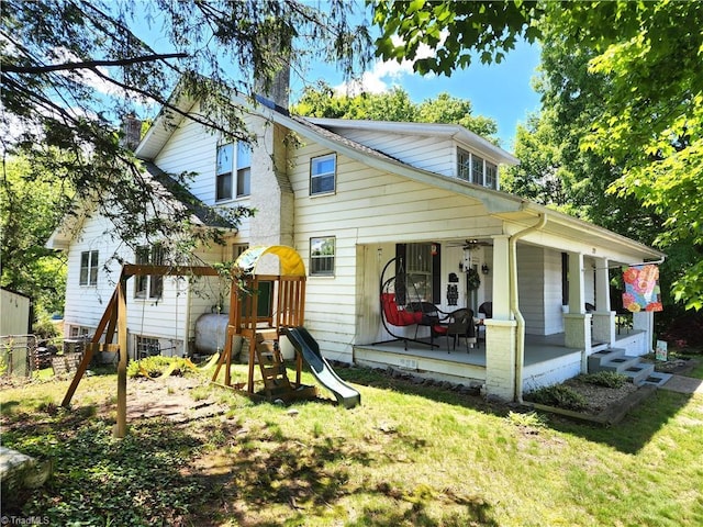 back of property with a chimney, a porch, and a playground