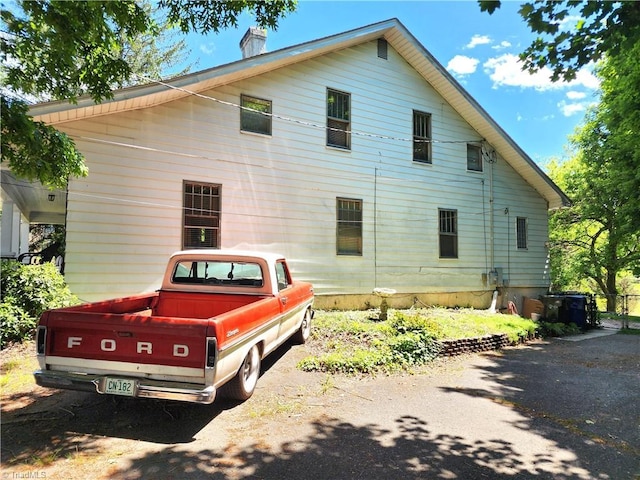 view of home's exterior with a chimney and driveway