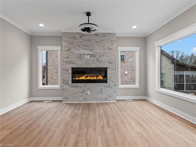 unfurnished living room with crown molding, a fireplace, and light wood-type flooring