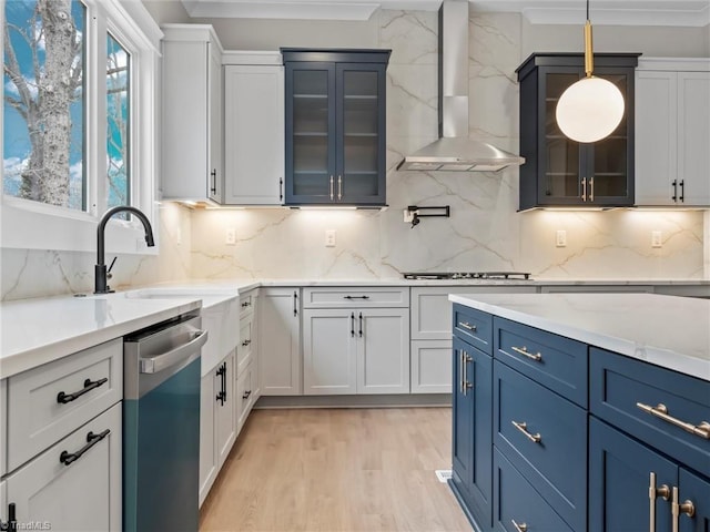 kitchen with stainless steel appliances, pendant lighting, white cabinets, and wall chimney exhaust hood