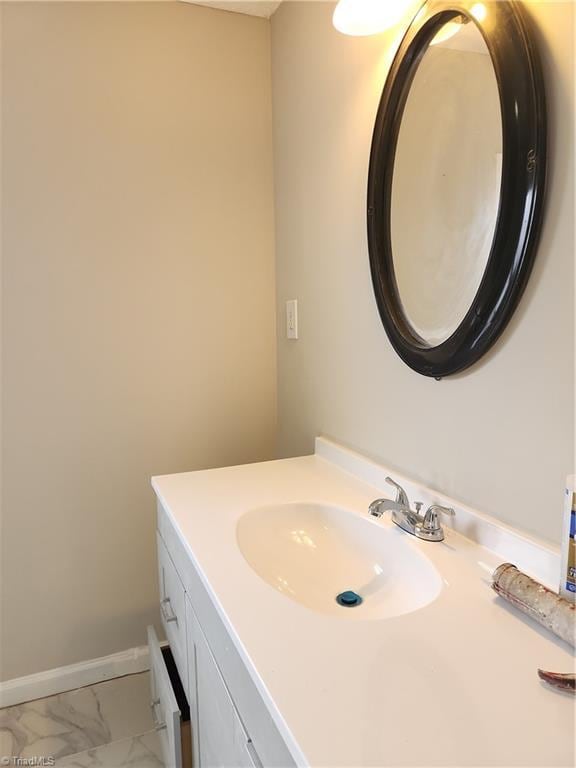 bathroom with marble finish floor, vanity, and baseboards