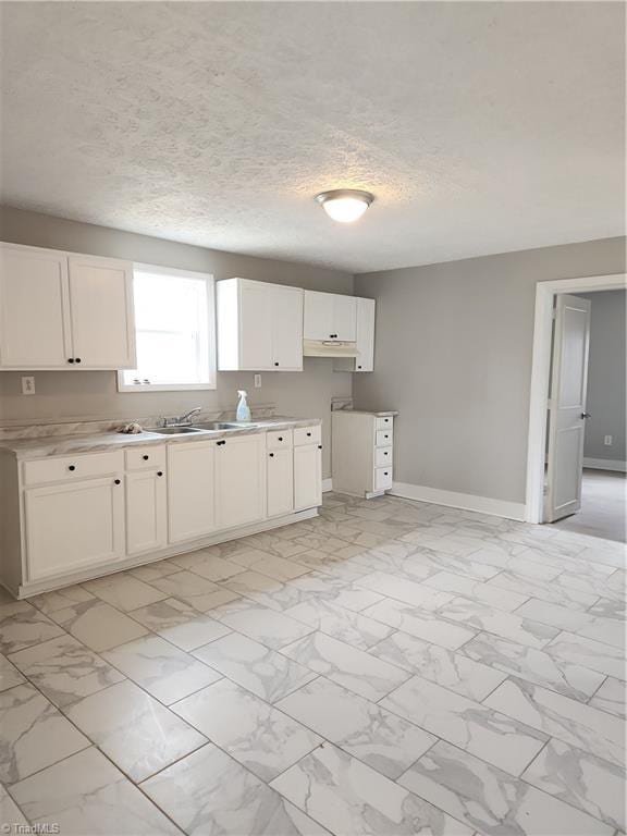 kitchen featuring marble finish floor, light countertops, and baseboards