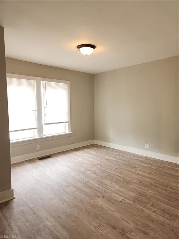 spare room with visible vents, baseboards, and wood finished floors