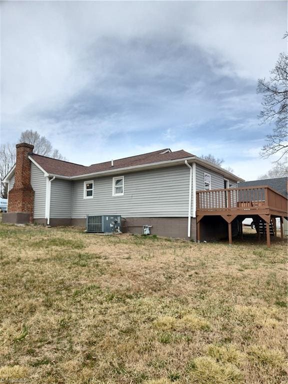 rear view of property with a chimney, a lawn, a deck, and central AC unit