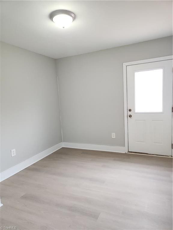 empty room featuring light wood-type flooring and baseboards