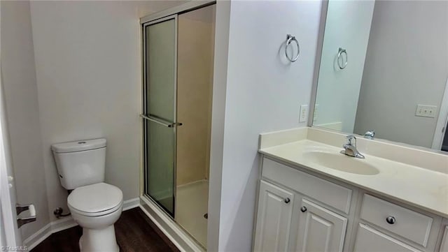 bathroom featuring a stall shower, toilet, wood finished floors, and vanity