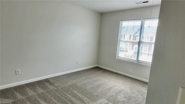 empty room with a wealth of natural light, visible vents, carpet flooring, and baseboards