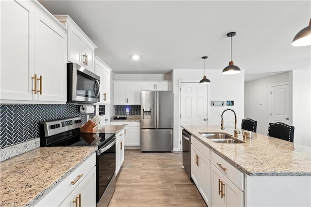 4514 Heatherly Rd, Winston-Salem, NC 27105 - kitchen with appliances with stainless steel finishes, tasteful backsplash, white cabinets, light wood-style flooring, and an island with sink