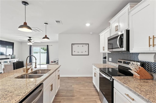 4514 Heatherly Rd, Winston-Salem, NC 27105 - kitchen with stainless steel appliances, light wood-style flooring, tasteful backsplash, decorative light fixtures, and white cabinets