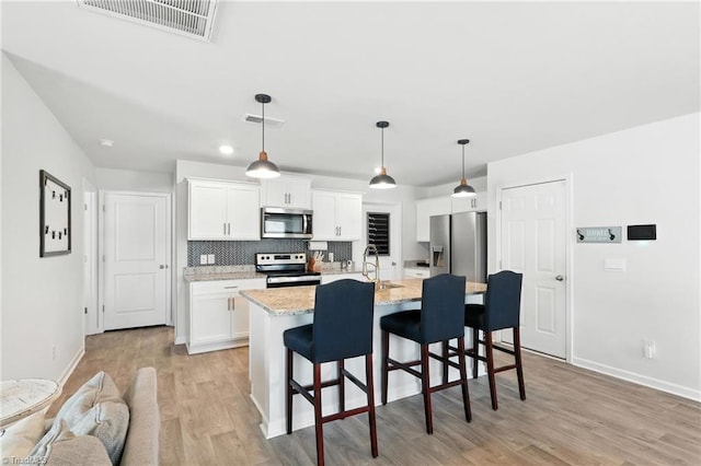 4514 Heatherly Rd, Winston-Salem, NC 27105 - kitchen featuring stainless steel appliances, light wood-type flooring, a kitchen breakfast bar, backsplash, and white cabinets