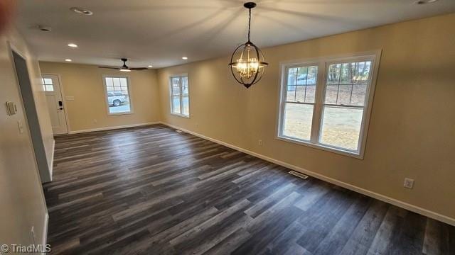 unfurnished dining area with ceiling fan with notable chandelier and dark hardwood / wood-style floors