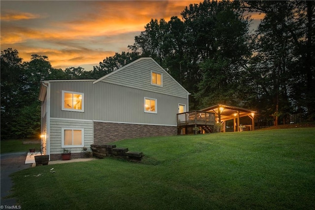 back house at dusk with a wooden deck and a yard