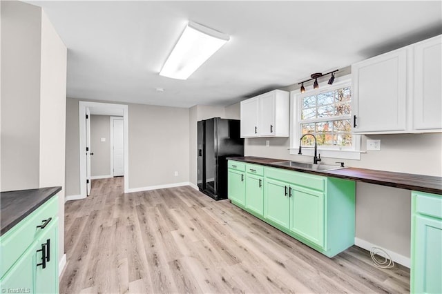 kitchen featuring black fridge, sink, light hardwood / wood-style flooring, white cabinets, and butcher block countertops