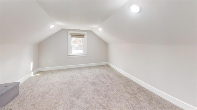 additional living space featuring light carpet and vaulted ceiling