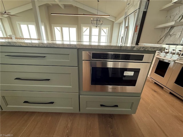 3048 Island Dr, Northtopsail Beach, NC 28460 - kitchen with light wood-type flooring, a healthy amount of sunlight, stainless steel oven, and light stone counters