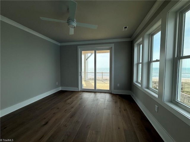 3048 Island Dr, Northtopsail Beach, NC 28460 - spare room featuring dark wood-style flooring, ornamental molding, baseboards, and a healthy amount of sunlight