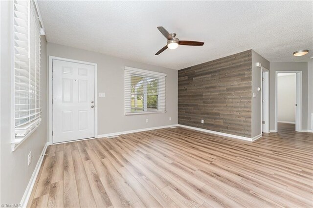 4104 Old Greensboro Rd, Winston-Salem, NC 27101 - unfurnished living room featuring ceiling fan, wood walls, light wood-style flooring, a textured ceiling, and baseboards