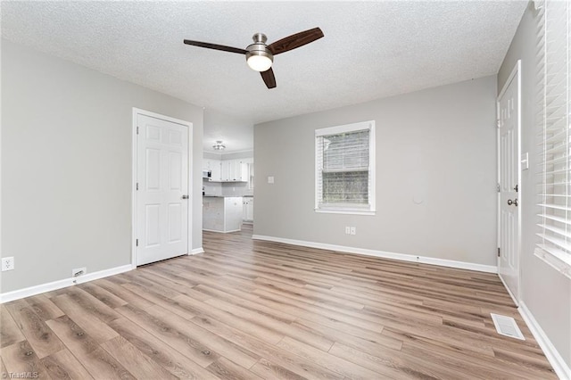 4104 Old Greensboro Rd, Winston-Salem, NC 27101 - unfurnished living room featuring a ceiling fan, light wood-type flooring, a textured ceiling, and baseboards
