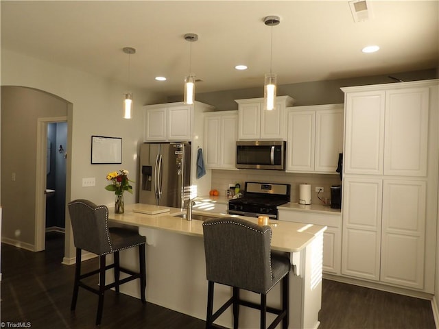5304 Smoky Ridge Ln, Winston-Salem, NC 27127 - kitchen with stainless steel appliances, arched walkways, a kitchen breakfast bar, dark wood finished floors, and white cabinets