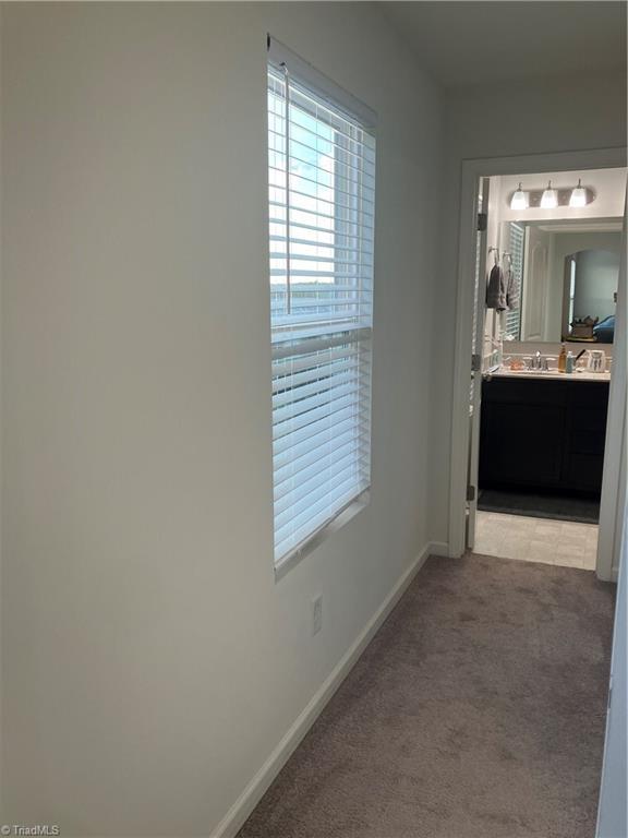 5304 Smoky Ridge Ln, Winston-Salem, NC 27127 - corridor featuring light colored carpet, baseboards, and a sink