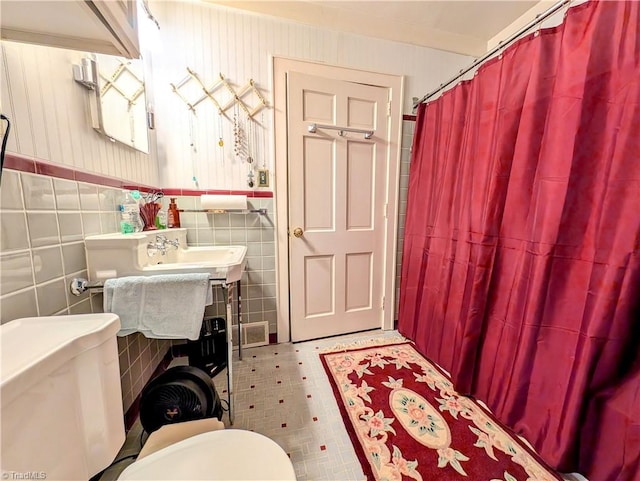 bathroom featuring toilet and tile walls