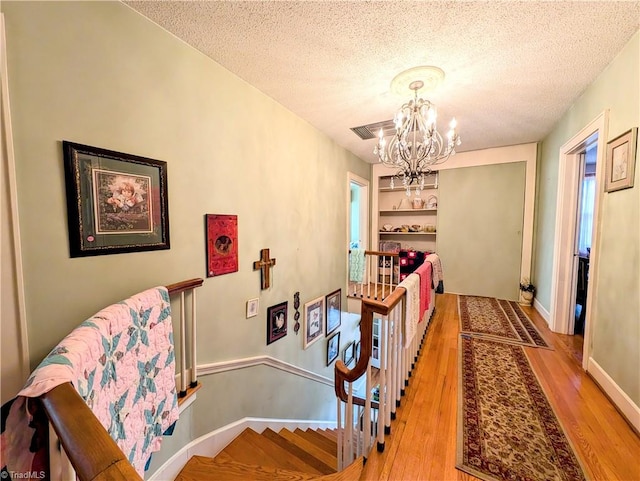 dining area featuring built in features, a textured ceiling, light wood-type flooring, and a notable chandelier