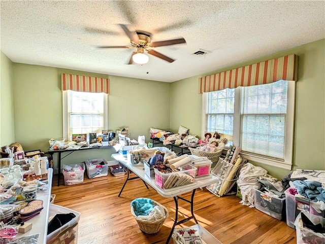 miscellaneous room with light wood-type flooring, a textured ceiling, ceiling fan, and plenty of natural light